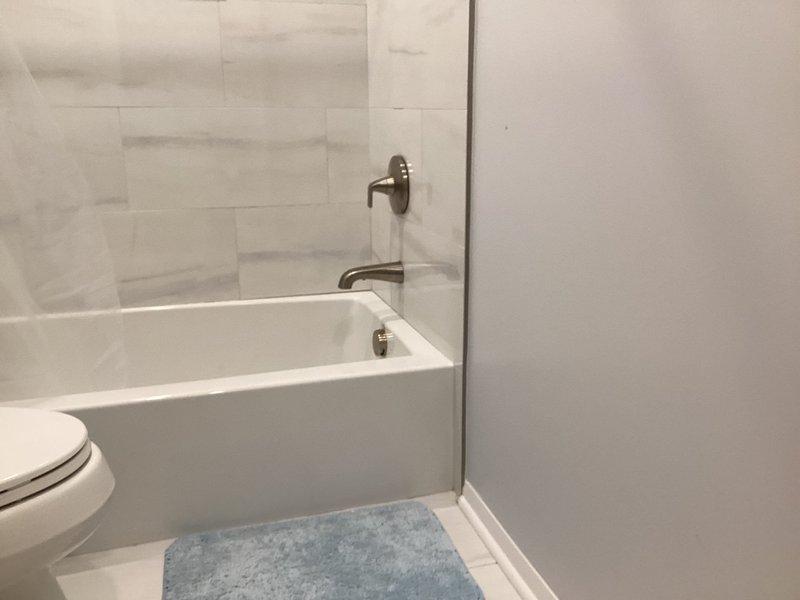 Responded to emergency call for hall bathroom tub faucet malfunction where water was bypassing the spout and leaking behind the wall instead of flowing properly through the fixture. Accessed the property during tenant turnover window, diagnosed failed tub spout diverter mechanism, and replaced the defective wall-mounted tub spout with new brushed nickel fixture. Verified proper water flow through spout, tested shower diverter function, inspected wall cavity for water damage, and confirmed no leaks present after installation.
