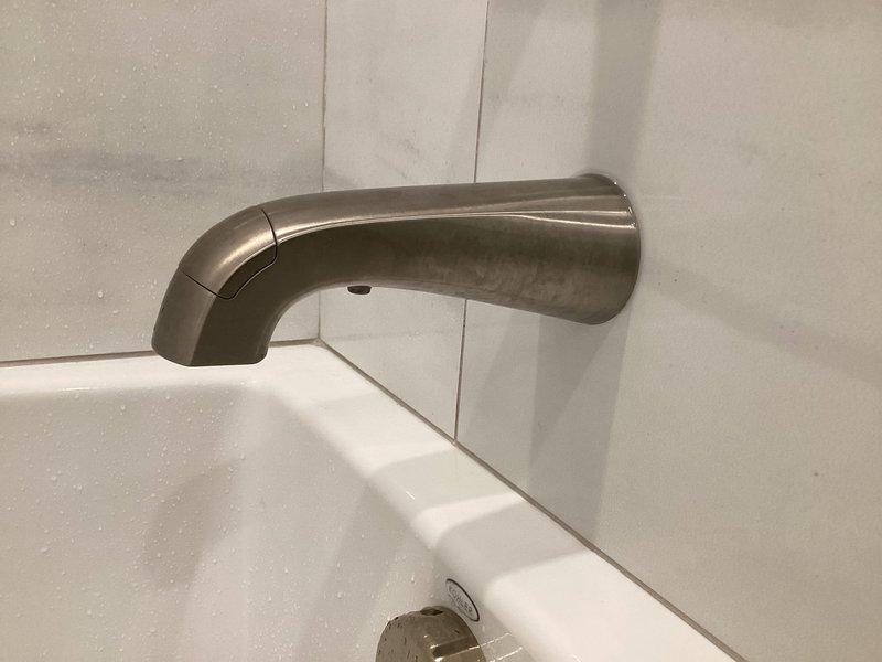 Responded to emergency call for hall bathroom tub faucet malfunction where water was bypassing the spout and leaking behind the wall instead of flowing properly through the fixture. Accessed the property during tenant turnover window, diagnosed failed tub spout diverter mechanism, and replaced the defective wall-mounted tub spout with new brushed nickel fixture. Verified proper water flow through spout, tested shower diverter function, inspected wall cavity for water damage, and confirmed no leaks present after installation.