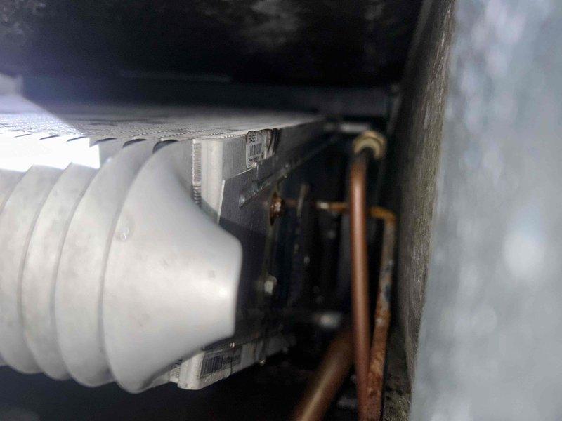 Responded to no cooling complaint on residential HVAC system. Upon inspection, found evaporator coil showing signs of restricted airflow with visible debris accumulation on fin surfaces. Examined refrigerant lines and condensate drainage system in attic installation - all connections secure with no visible leaks. Documented system conditions with photos showing coil contamination and ductwork configuration. Customer advised system not maintaining temperature setpoint due to reduced airflow across evaporator coil, requiring additional service to restore proper cooling capacity.