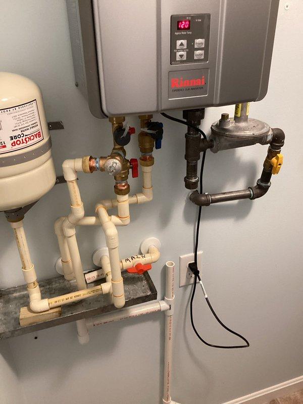 Removed and disposed of existing water heating system. Installed new Rinnai RE199iP tankless water heater with complete water supply connections, gas line hookup, and proper venting system. Configured all necessary plumbing connections including hot and cold water lines with shutoff valves, expansion tank, and pressure regulation components. Installed PVC exhaust venting through ceiling with appropriate mounting hardware and gasket seals. Connected gas supply line with shutoff valve and completed all electrical connections. System tested and operational, displaying proper temperature readings on digital control panel.