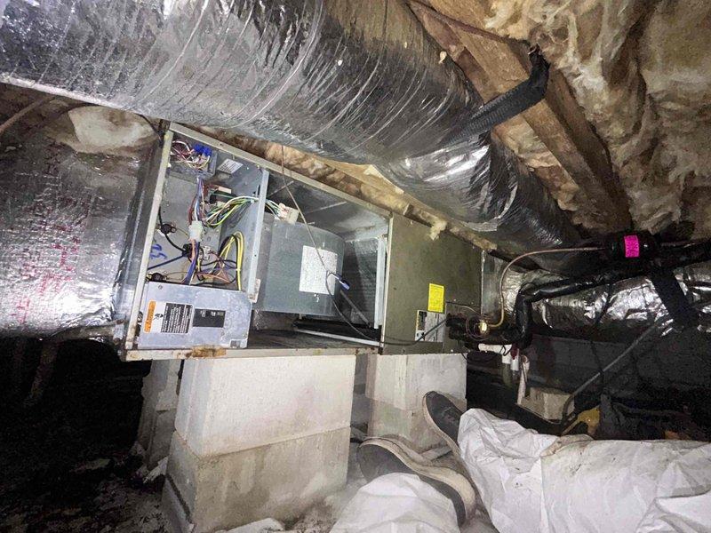 Responded to no-cooling call on downstairs system where outdoor unit was running but no airflow was present. Upon inspection in crawlspace, found air handler with wiring exposed during troubleshooting and confirmed lack of blower operation. Instructed customer to shut system off and set thermostat fan to "on" position to verify blower motor functionality independently of cooling cycle, isolating the issue to indoor air handler components rather than outdoor condensing unit.