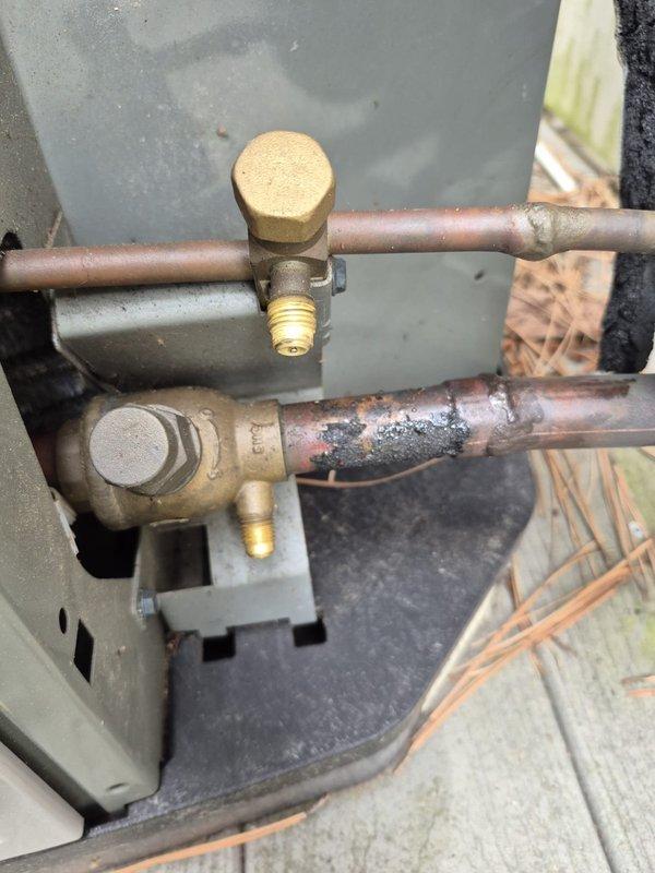 Responded to report of water leak through ceiling originating from air handler unit Q150+BT. Upon inspection, found evidence of condensate drainage issue at the air handler. Inspected and photographed the air filter, which showed typical dust accumulation and required replacement. Examined refrigeration line connections and service valves on outdoor unit, noting weathered copper piping with surface oxidation and corrosion on lower valve assembly. Addressed leak source and documented equipment condition for service records.