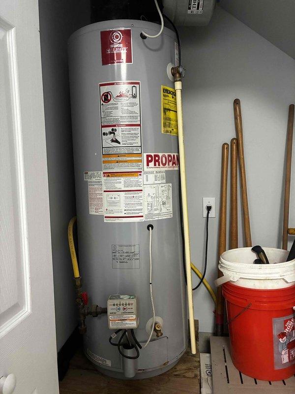 Completed estimate for residential water heater replacement. Evaluated existing propane-fired State brand water heater installation in utility closet, documenting current configuration including yellow flexible gas lines, copper supply piping, expansion tank, and venting system. Assessed feasibility of conventional tank replacement versus tankless conversion, photographing existing plumbing connections, gas line routing, electrical components, and spatial constraints within confined installation area for customer review and proposal preparation.