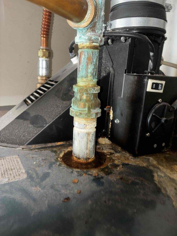 Responded to no hot water complaint at residential property. Upon arrival, inspected tanked water heater installation located in utility cabinet. Verified electrical supply by checking breaker panel - confirmed breaker was functioning properly and in correct position. Performed diagnostic assessment of water heater unit and associated plumbing components including PVC piping, expansion tank, and copper supply lines. Observed significant corrosion on vertical piping with blue-green oxidation, mineral deposits, and rust staining present. Noted deterioration at pipe penetration point with heavy oxidation radiating from base connection. Inspected circulation pump assembly and brass fittings for proper operation. Documented equipment condition through photographic evidence showing corrosion patterns and component wear. Advised customer of findings and recommended monitoring for potential future repairs due to advanced corrosion observed on piping system. Unit operational upon completion of 
