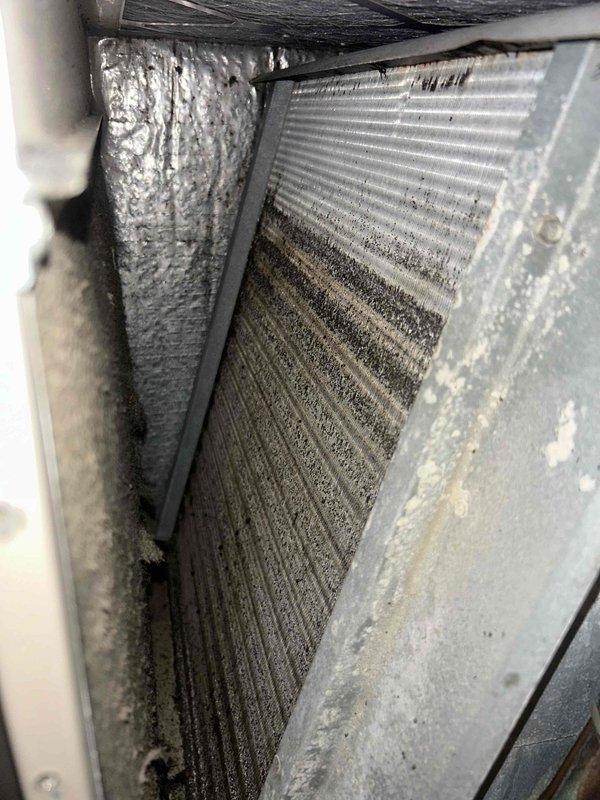 # HVAC Maintenance - Cooling System Service

Performed routine cooling maintenance visit on residential air handling unit. Upon inspection, discovered evaporator coils heavily soiled with significant dust, dirt, and debris accumulation throughout the fin surfaces, particularly in lower sections where buildup was most severe. The clogged condition was restricting airflow and reducing system efficiency.

Accessed air handler unit and replaced air filter as part of standard maintenance protocol. Documented existing coil condition with photographs showing extent of contamination on heat exchanger fins and internal components. The metallic fins displayed uneven deposits with darker, thicker accumulation in concentrated areas, indicating extended operation without recent cleaning.

Inspected ductwork connections and cabinet housing, noting normal wear consistent with system age. All accessible components were visually examined for proper operation. System measurements were taken and recorded