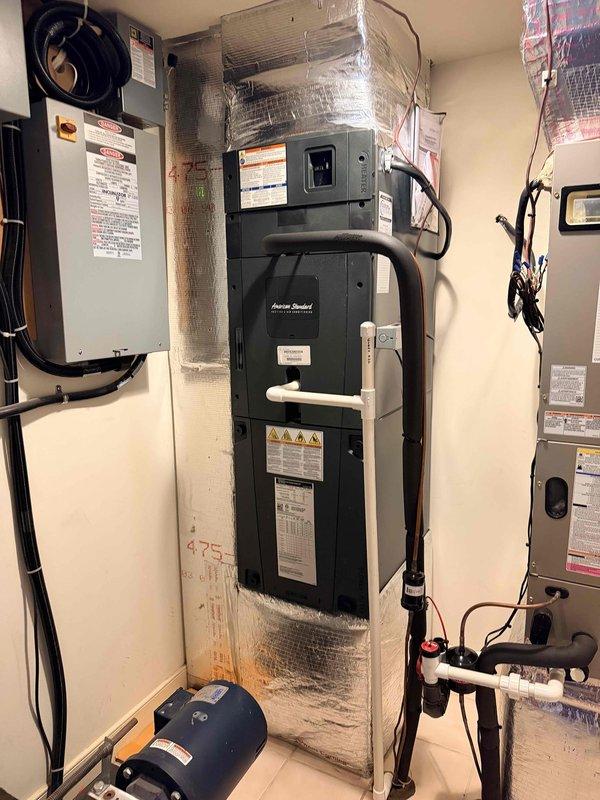 Performed scheduled cooling maintenance visit on residential HVAC system. Inspected air handler unit, water heater, and associated mechanical equipment in utility room. Documented current equipment conditions including American Standard water heater with reflective insulation, electrical panel connections, PVC drainage lines, refrigerant piping with service valves, and circulation pump components. All equipment photographed for service records and system operational status verified.