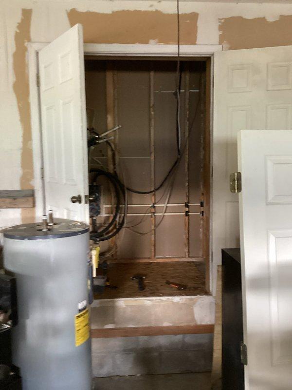 Conducted plumbing estimate for fixture installation in a residential property undergoing renovation. Assessed existing conditions including a laundry room area with damaged drywall, exposed electrical boxes, and a washing machine, as well as a utility closet containing a water heater with copper piping and black flexible supply lines. Documented multiple copper supply lines running vertically through the utility space and evaluated the infrastructure for planned fixture upgrades or replacements in the renovation project.