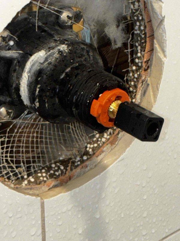 Responded to rental property for two reported issues in master bathroom: no hot water and loose shower handle preventing temperature adjustment. Accessed shower valve through wall opening to diagnose hot water supply issue isolated to master bathroom while rest of house had proper hot water function. Inspected and tightened loose shower handle mechanism to restore proper temperature control operation. Documented existing conditions with photos showing valve assembly access point and plumbing components for reference.