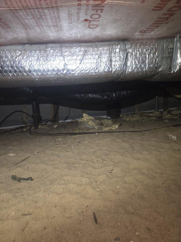 Responded to no cooling complaint on heat pump system over 10 years old. Upon arrival, accessed unit and performed system diagnostics. Customer reported excessive airflow to powder room, suspecting ductwork imbalance. Inspected crawl space ductwork and found flexible duct runs with potential airflow distribution issues. Documented system conditions with photos showing spray foam insulated ceiling areas, flexible aluminum ductwork, and overall crawl space infrastructure. Assessed duct routing, support strapping, and insulation integrity throughout accessible areas. Identified ductwork configuration contributing to uneven air distribution between zones. Provided recommendations for ductwork modifications to balance airflow and address comfort concerns in affected room.