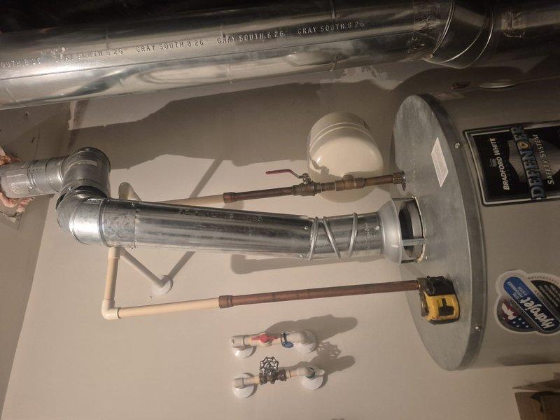 Conducted on-site evaluation of existing residential water heater system located in utility room. Inspected current gray cylindrical water heater unit, documented manufacturer specifications, control panel functionality, and overall condition of installation. Assessed plumbing connections including copper supply lines, PVC drainage system, flexible hoses, and shut-off valve configuration. Evaluated HVAC ductwork proximity and clearance requirements. Provided comprehensive estimate for water heater replacement including removal of existing unit and installation of new system with proper code-compliant connections.
