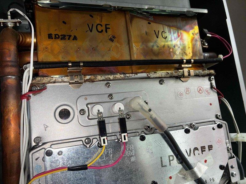 Responded to no-heat call for tankless water heater system. Upon inspection, found unit experiencing operational failure with control board and internal component issues. Accessed interior control panel and electrical connections, identifying worn wiring harnesses and deteriorated terminal connections. Documented internal condition showing significant dust and debris accumulation affecting system performance. Inspected heat exchanger panels displaying heat stress discoloration and age-related wear. Evaluated gas valve assembly, copper piping connections, and electrical wiring integrity throughout unit. Photographed control board assembly, safety warning labels, and internal components for service documentation and future reference.
