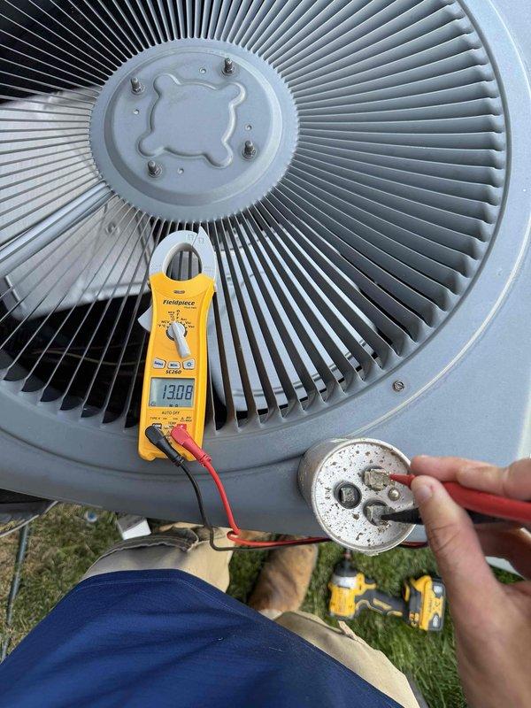 Responded to no cooling complaint on 6-year-old Goodman system in basement installation. Upon arrival, confirmed unit was blowing warm air. Performed diagnostic testing and found failed run capacitor with visible corrosion and deterioration on terminals. Measured capacitance at 13.08 microfarads, significantly below rated specification. Outdoor condenser unit showed extensive weathering and white oxidation buildup on compressor terminal plate with rust staining throughout. Documented component condition with photos for approval. Replaced defective capacitor with OEM equivalent part. Verified proper compressor amperage draw and confirmed system returned to normal cooling operation. Tested airflow at supply registers and verified temperature split within manufacturer specifications. System operating efficiently upon departure.