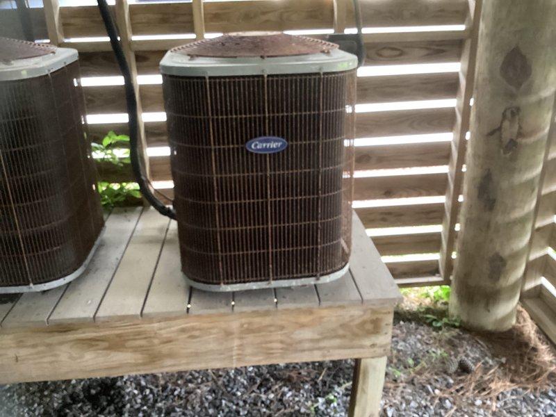 Conducted on-site evaluation of existing HVAC system for complete replacement. Current equipment includes aging Carrier outdoor condenser units mounted on wooden platforms in exterior side yard area, with indoor air handler located in garage ceiling space. Documented existing system configuration, equipment placement, and installation conditions through photographic assessment. Provided comprehensive replacement estimate for new complete HVAC system installation.