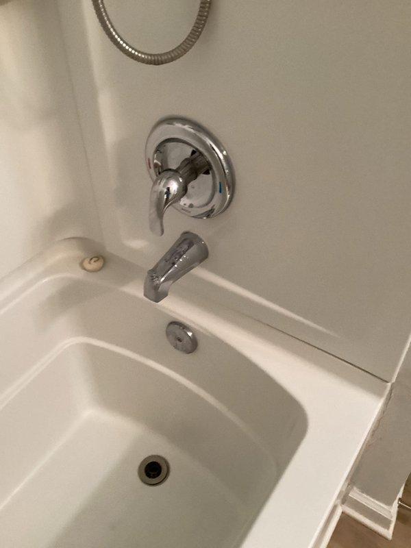 Responded to service call for tub leaking into carport overhang area below bathroom. Upon arrival, accessed property via lockbox at hose bib and conducted thorough inspection of bathtub, shower assembly, and surrounding fixtures. Examined white fiberglass tub/shower combination unit, chrome faucet assembly with single-handle lever control, overflow drain, and primary drain opening for signs of active leaks or water damage. Photographed bathtub installation and adjacent flooring areas to document conditions. Advised property owner to contact restoration services regarding potential water damage to carport ceiling and overhang structure prior to completing permanent repairs.