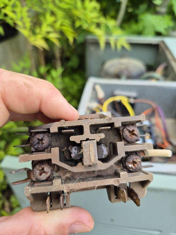 Responded to no cooling complaint on residential HVAC system. Upon inspection, discovered heavily corroded contactor with significant rust and deterioration on metal contact points, insulating blocks, and mounting hardware. Contactor showed extensive oxidation and environmental damage from prolonged outdoor exposure, preventing proper electrical contact closure. Removed failed contactor, installed new replacement unit, and restored cooling operation to system.