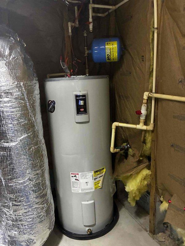 Reinstalled existing tanked water heater unit in mechanical room after another contractor had disconnected and removed it earlier in the day. Connected all water supply lines, pressure tank connections, and plumbing fittings to restore the system to operational status. Verified proper installation of the white cylindrical water heater with digital control panel, ensuring all copper piping, PVC connections, and safety components were properly secured and functional.