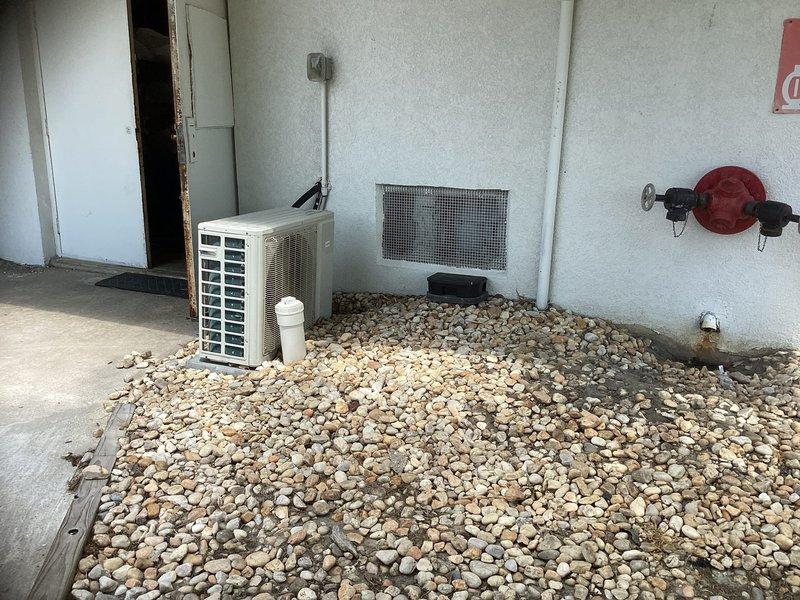 Completed estimate for ductless mini-split system installation in machine room with concrete block walls. Assessed outdoor condenser placement location on gravel pad adjacent to existing HVAC equipment and evaluated interior mounting position for air handler unit with consideration for electrical conduit routing and connection requirements.