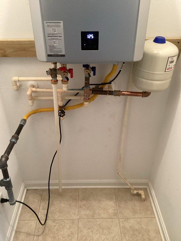 Removed and disposed of existing tank-style water heater and exhaust flue system. Installed new Rinnai RX199i tankless water heater unit with expansion tank, brass service valve kit, and 3/4" male high-temperature connections. Ran 40 feet of 2" PVC Schedule 40 pipe for exhaust venting system using four 2" PVC DWV 90-degree elbows, two 45-degree elbows, and two couplings to route flue piping from unit to existing roof penetration. Installed 2" concentric assembly with roof termination cap and waterproof boot at roof exit point. Connected all water supply lines, gas piping, and electrical components per manufacturer specifications. System tested and operational at 125 degrees, with all connections verified leak-free and unit functioning properly.