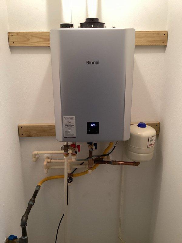 Removed and disposed of existing tank-style water heater and exhaust flue system. Installed new Rinnai RX199i tankless water heater unit with expansion tank, brass service valve kit, and 3/4" male high-temperature connections. Ran 40 feet of 2" PVC Schedule 40 pipe for exhaust venting system using four 2" PVC DWV 90-degree elbows, two 45-degree elbows, and two couplings to route flue piping from unit to existing roof penetration. Installed 2" concentric assembly with roof termination cap and waterproof boot at roof exit point. Connected all water supply lines, gas piping, and electrical components per manufacturer specifications. System tested and operational at 125 degrees, with all connections verified leak-free and unit functioning properly.