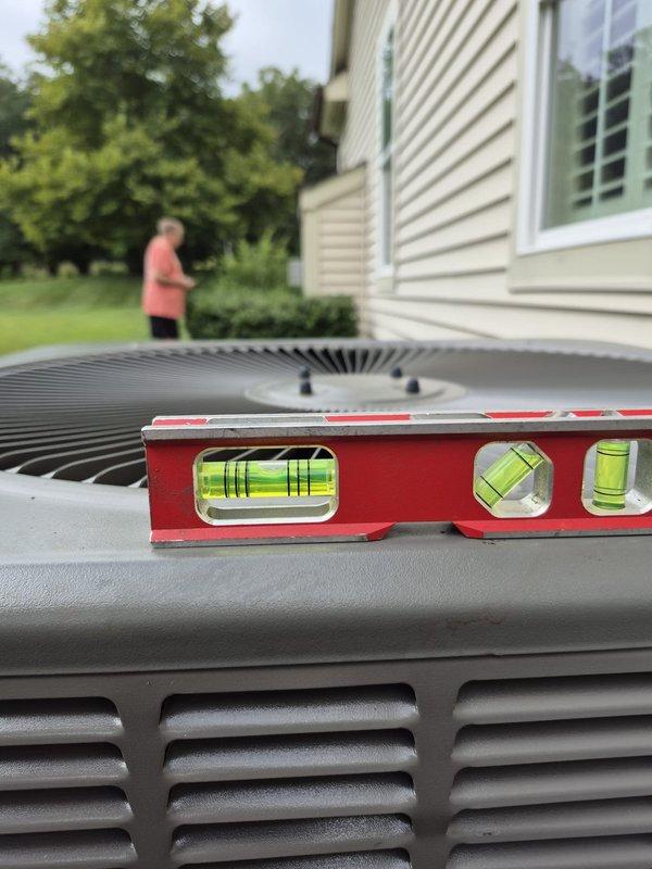 Responded to service call for recently installed HVAC system with concerns about condensing unit stability. Upon arrival, confirmed unit was sitting at an angle on wooden platform base, which had shifted from its original position. Used level to verify unit was not properly aligned, which can affect performance and potentially cause compressor damage over time. Documented condition with photos showing both the angled positioning and level measurements. Rescheduled return visit to properly level and secure both outdoor units on their wooden platforms to ensure stable operation and prevent future mechanical issues.