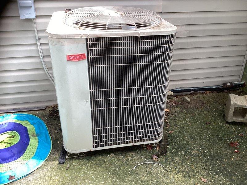 Provided estimate for complete split system replacement of aging Bryant R-22 system. Existing outdoor condenser unit shows significant weathering, paint oxidation, and environmental wear with algae growth on concrete pad. Indoor air handler located in utility room requires replacement along with outdoor unit due to obsolete R-22 refrigerant. Customer reviewing multiple contractor estimates before proceeding with system upgrade.