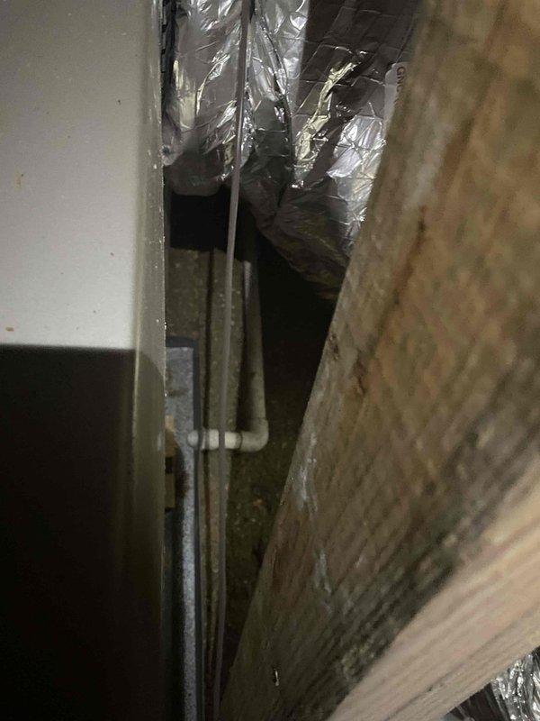 Responded to no cooling complaint on residential split system. Property for sale with recent service by another contractor, unit subsequently failing to maintain temperature. Performed diagnostic evaluation of outdoor condensing unit and indoor air handler system. Inspected condenser fan operation, refrigerant circuit, and electrical components. Examined attic-mounted air handler and ductwork installation for proper airflow and system performance. Documented equipment condition with photos showing outdoor unit placement on mulch bed against building exterior and indoor components in attic space with flexible ductwork visible. Unit not maintaining adequate cooling capacity despite previous service attempt.