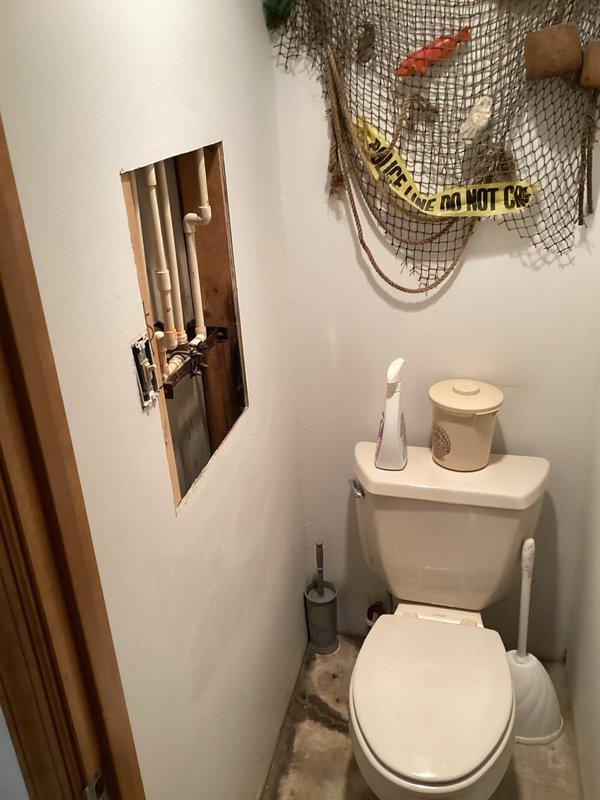Responded to service call for slow leak in downstairs shower room with water visible along concrete edge between shower and adjacent toilet room. Upon inspection, discovered significant water staining on shower floor indicating ongoing moisture intrusion. Created wall access opening to expose plumbing lines and investigate source of leak behind shower wall. Inspected copper supply lines and drain connections within wall cavity to identify leak location potentially related to previous plumbing work performed at property. Documented conditions with photographs showing extent of shower floor discoloration and exposed plumbing components for further evaluation and repair recommendations.