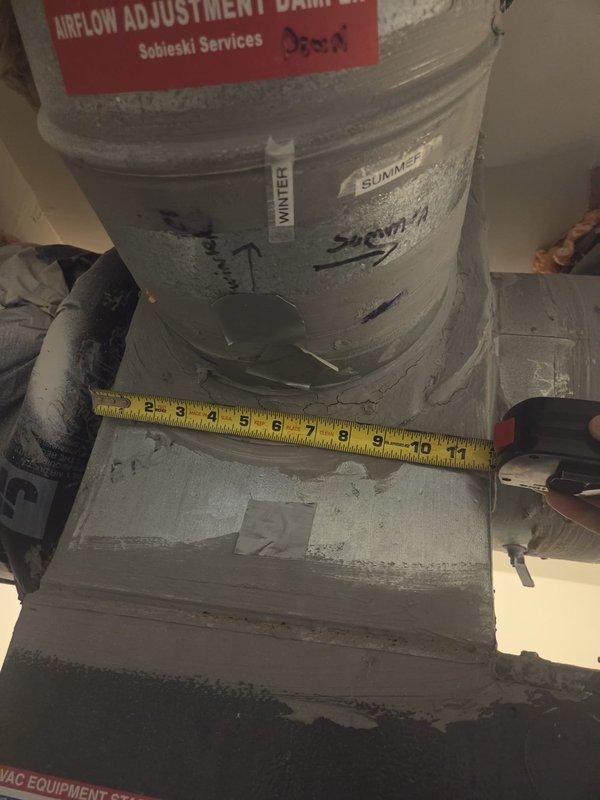 Responded to emergency service call for air handler leaking water into drain pan on eight-year-old system. Upon inspection, documented existing HVAC installation including air handler unit with insulated ductwork and airflow adjustment damper. Assessed unit for condensate drainage issues, photographed equipment configuration and measured components to verify proper installation and identify source of water accumulation in pan.