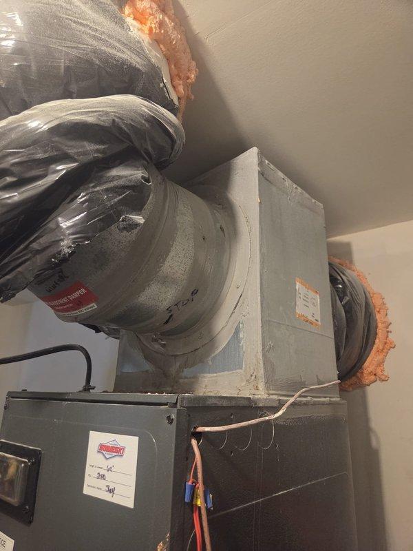 Responded to emergency service call for air handler leaking water into drain pan on eight-year-old system. Upon inspection, documented existing HVAC installation including air handler unit with insulated ductwork and airflow adjustment damper. Assessed unit for condensate drainage issues, photographed equipment configuration and measured components to verify proper installation and identify source of water accumulation in pan.