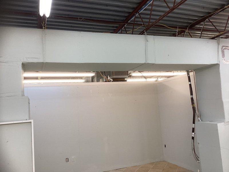 Conducted rooftop HVAC system evaluation for commercial building formerly used as furniture store. Assessed existing cylindrical air conditioning condenser unit elevated on wooden blocks, documented condition of electrical connections and wiring, and evaluated rooftop access via metal ladder to roof hatch. Provided comprehensive replacement estimate for complete system installation.