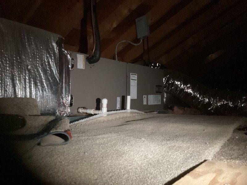 Conducted comprehensive assessment of existing HVAC system in attic space to provide replacement estimate. Evaluated air handler unit and associated ductwork configuration, identifying refrigerant deficiency requiring potential recharge with dye for leak detection. Documented critical drainage issue with upstairs system condensate line improperly terminating approximately one foot into soil near crawlspace entrance, requiring corrective drain work to ensure proper water evacuation and prevent foundation damage.