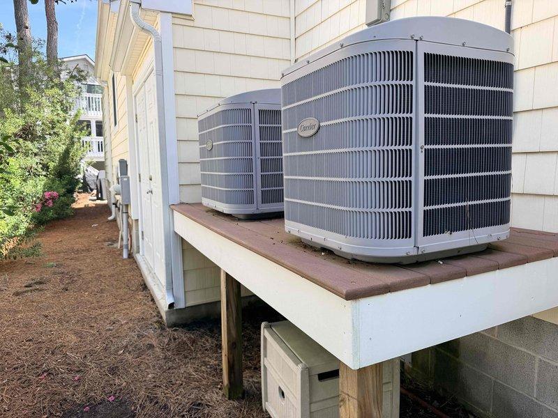 Conducted comprehensive site assessment for complete HVAC system replacement of dual-zone residential installation. Evaluated downstairs system located in interior closet with removable wall access panel and upstairs system positioned in attic space. Documented existing exterior equipment consisting of two Carrier condensing units mounted on elevated wooden platform along building exterior. Provided detailed replacement estimate for both complete systems including indoor air handlers and outdoor condensing units.