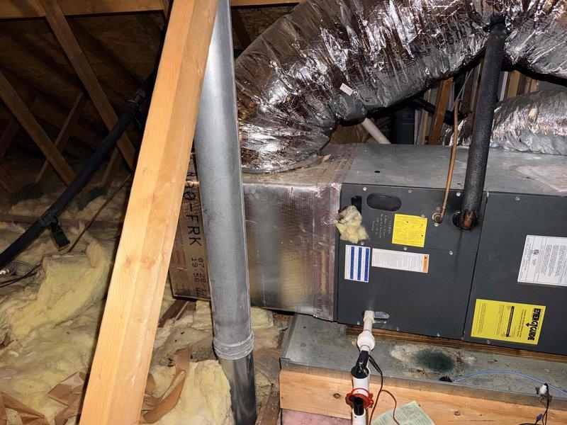Assessed 14-year-old HVAC system serving loft area that was reported out of refrigerant. Inspected attic-mounted air handler unit, deteriorated flexible ductwork, and associated components via pull-down attic access. Documented equipment condition and provided replacement system estimate due to age of unit and refrigerant loss.