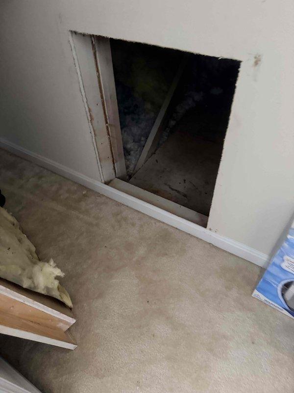 Conducted estimate for replacement of heat pump system located in storage space above garage serving loft area, one bedroom, and one bathroom. Current system is operational but showing age-related wear and deterioration requiring replacement. Accessed unit through wall opening in loft area, assessed existing equipment and installation conditions, documented current outdoor condenser unit configuration with multiple units present on exterior concrete pads, and provided comprehensive replacement options for aging HVAC system.