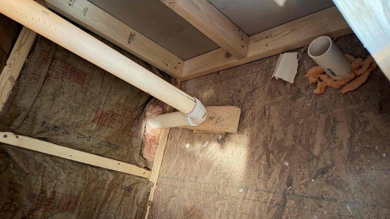 Conducted on-site assessment of finished attic space for ductless mini-split installation. Evaluated existing structural conditions including OSB flooring, exposed framing, fiberglass insulation, and current PVC plumbing runs to determine optimal equipment placement and line set routing. Documented space dimensions, electrical access points, and potential mounting locations for indoor air handler unit, while identifying exterior wall penetration requirements for refrigerant lines and condensate drainage to outdoor condenser unit.