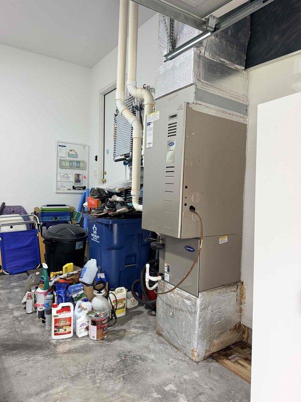 Conducted on-site evaluation of 21-year-old HVAC system located in garage for replacement estimate. Inspected existing furnace/air handler unit, ductwork connections, and associated components including condensate drainage lines and electrical connections. Documented current system condition through photographs showing equipment age, wear patterns, and installation configuration to provide comprehensive replacement recommendations.
