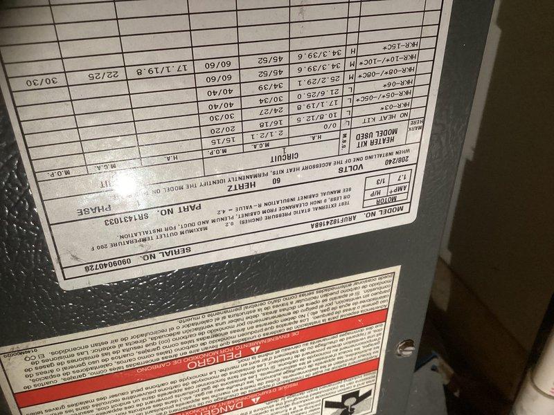 Conducted estimate for replacement of 16-year-old HVAC system consisting of air handler unit currently installed in main floor utility closet. Inspected existing dark green vertical air handler with return air filter grille, documented unit specifications from manufacturer labels, and photographed current installation including PVC condensate drain lines and confined closet space with louvered door access for replacement planning purposes.