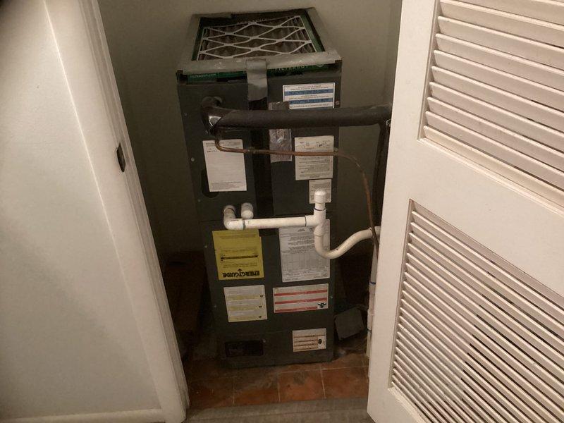 Conducted estimate for replacement of 16-year-old HVAC system consisting of air handler unit currently installed in main floor utility closet. Inspected existing dark green vertical air handler with return air filter grille, documented unit specifications from manufacturer labels, and photographed current installation including PVC condensate drain lines and confined closet space with louvered door access for replacement planning purposes.