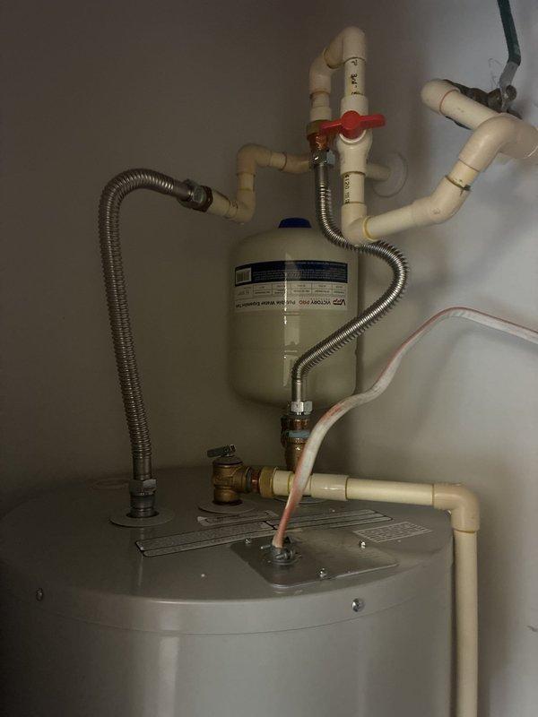 Installed a Bradford White 50-gallon electric water heater (model PE250T6-1NCWW) with 4500W dual heating elements rated for 240V operation. Installation included a 22-inch drain pan for leak protection, thermal expansion tank to accommodate system pressure fluctuations, and complete plumbing connections using brass fittings (3/4" nipples in 2" and 6" lengths, 90-degree elbow, tee fitting), high-temperature rated dielectric unions, and 18-inch flexible water connectors. Unit was integrated with existing water filtration system and properly configured with shut-off valves for safe operation and future maintenance access.