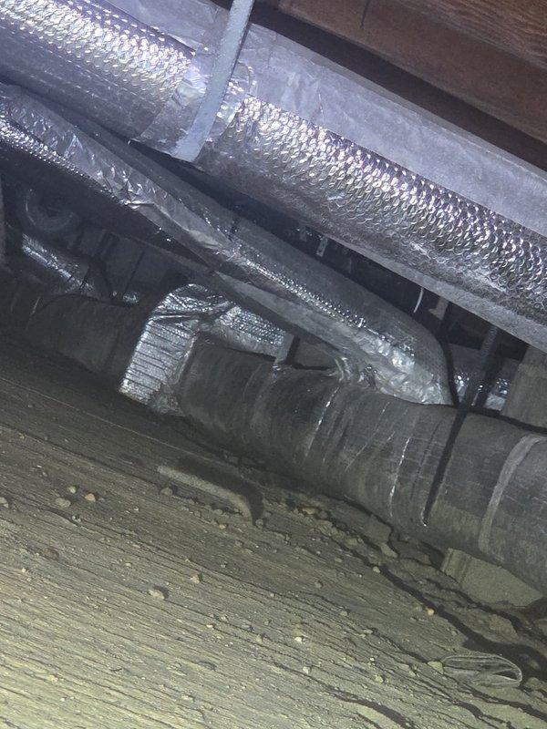 Completed comprehensive heating system maintenance inspection in residential property. Inspected HVAC ductwork system located in attic and basement areas, including insulated supply ducts with reflective wrap material and refrigerant line runs. Documented condition of air distribution components and identified moisture concerns on foundation wall near mechanical equipment requiring future attention.