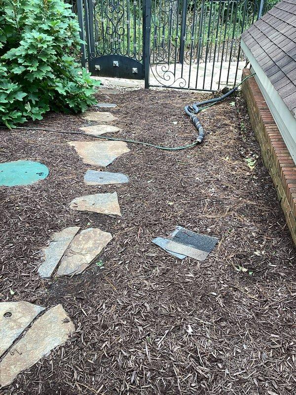 Completed reset of toilet in downstairs full bathroom and inspected remaining toilets in residence to ensure proper operation. Relocated and secured water conditioner discharge hose to prevent freezing damage during winter months and eliminate tripping hazard across walkway. Hose was previously routed across stone pathway where it was exposed to foot traffic and potential freeze conditions; repositioned hose along building perimeter and secured to prevent future issues.