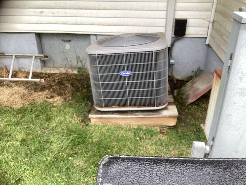 Conducted comprehensive site assessment for HVAC system replacement at residential property with attic access via ladder. Evaluated existing outdoor condensing unit positioned on wooden platform and inspected soffit ventilation panel for proper attic airflow considerations. Documented current equipment configuration and structural access points to prepare detailed replacement estimate for complete system upgrade.
