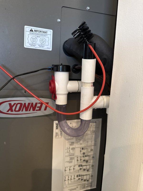 Responded to non-emergent service call regarding condensate line installation concern following recent HVAC system installation. Upon arrival, found plastic condensate drain line protruding from bi-fold closet door opening where indoor air handler unit is located. Accessed Lennox air handler unit inside closet, assessed existing PVC condensate piping configuration and routing. Repositioned and secured condensate drain line to ensure proper clearance from bi-fold door operation, preventing interference and improving aesthetic appearance. Verified condensate drainage system functionality and confirmed proper pitch for gravity drainage. Documented completed work with photographs showing unit interior with PVC drain assembly and T-fitting configuration, as well as exterior view of closet door area. System operating properly with no further concerns noted.