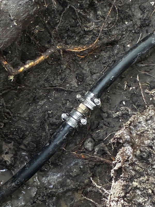 Completed main water line service repair by excavating to expose the damaged section of the supply line. Installed repair clamps with stainless steel hose clamps to secure the compromised pipe section and restore water service integrity. Backfilled the trench with excavated soil and hand raked the surface to grade level, completing the emergency repair and restoring full water service to the property.