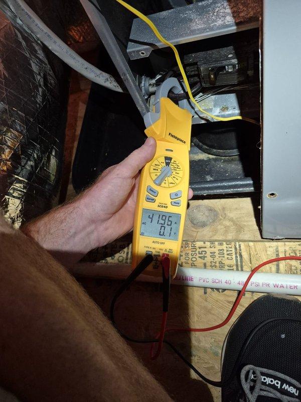 Performed scheduled heating maintenance on the system, including electrical testing of the control and power circuits using a clamp meter to measure amperage draw on the unit's wiring and components. Inspected the electrical compartment, wiring harness, and contactor/capacitor components, and checked the surrounding insulated ductwork and condensate PVC drain line in the attic space. System operation was verified, with no further issues noted at completion.