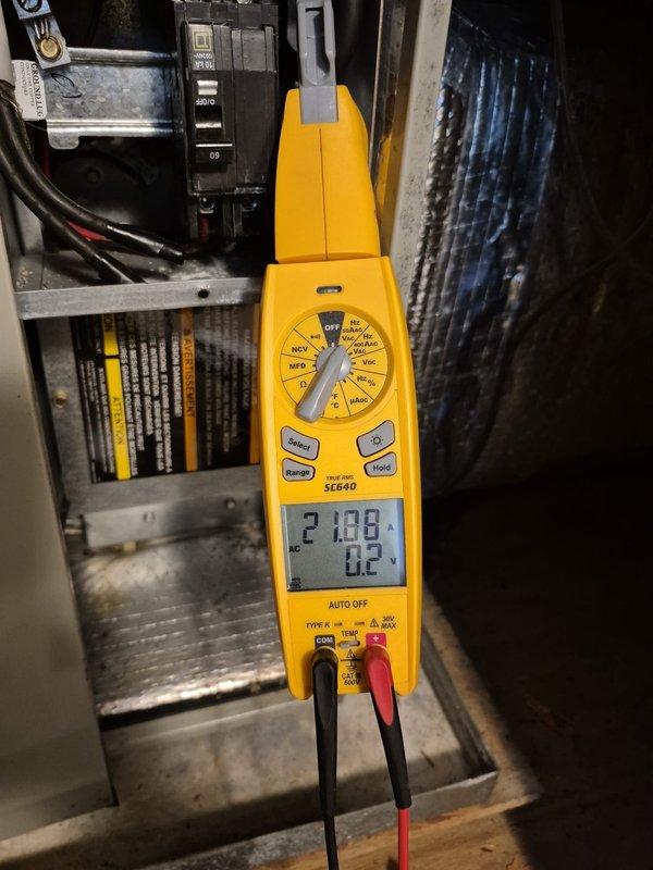 Performed seasonal heating maintenance on an 11-year-old heat pump system, inspecting the outdoor condensing unit's electrical compartment, contactor, capacitor, and wiring connections. Measured amperage draw with a clamp meter at both the air handler (21.88 A) and the condensing unit (5.30 A) to verify electrical components were operating within normal parameters. System confirmed operational and ready for heating season.