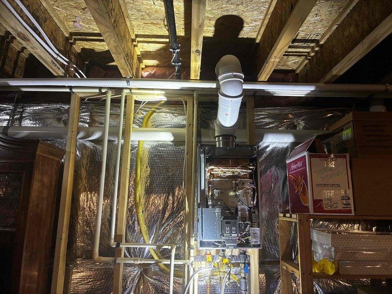 Renewed the pressure/temperature-rated unit components on the wall-mounted tankless water heater, with the front cover removed to access the internal control board, copper tubing, and wiring. Inspected the gas supply line, water connections, and PVC venting, and verified the exterior vent terminations were intact and unobstructed. Flagged a potential natural gas conversion for follow-up.