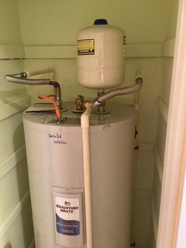 Removed the leaking water heater and installed a new 50-gallon tall Bradford White tank-type unit. Installed a new drain pan, thermal expansion tank, brass nipples, tee, and fittings, and connected the water lines with 18" flexible connectors. Verified all connections are secure with no leaks and the unit is operating properly.