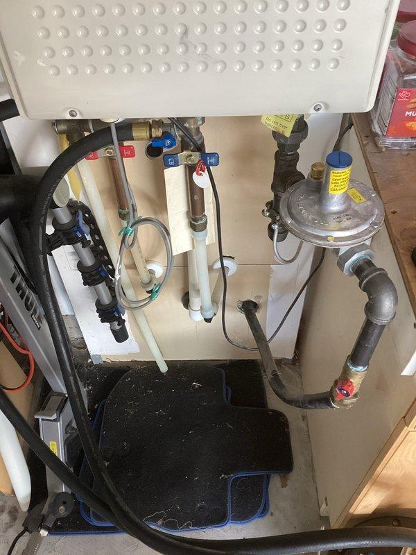 Performed annual maintenance on a wall-mounted tankless water heater, including a heat check and a descaling flush using a recirculation setup with isolation valves and a bucket. Inspected the water and gas connections, regulator, shutoff valves, and venting, and found no leaks, corrosion, or visible defects.