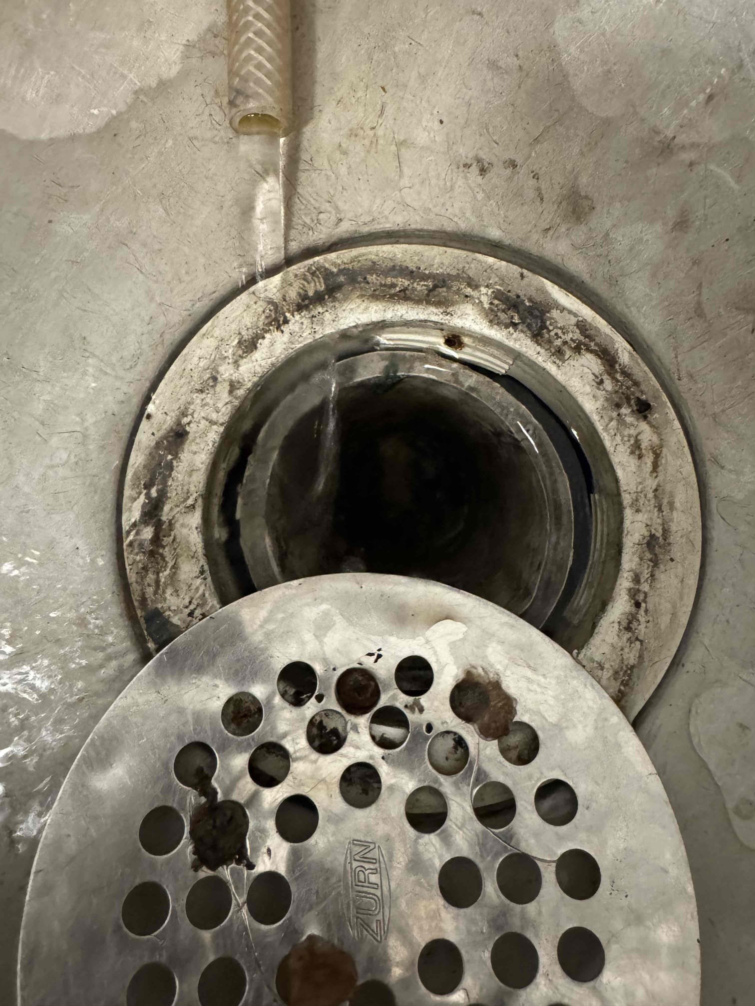 Upon inspection, the mop lock ring and seal were found to be severely damaged, causing the mop sink to leak. The seal had been pushed down around the drain pipe, exacerbating the issue. The constant water flow from the air conditioning machines, which were running continuously, contributed to the leakage. The sink, a standard 24x24 mop sink, required replacement. The surrounding wall and tile corners added complexity to the extraction process, necessitating the assistance of two individuals. The air conditioning machines were removed to facilitate the repair. Following these steps, the mop sink ceased leaking until a replacement could be installed.